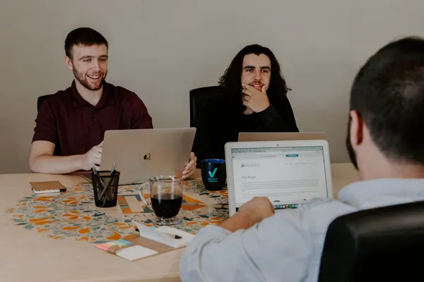 A few tech people with computers at a hackathon event.