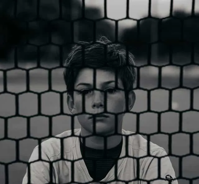A young boy looking into the camera who is quite sad
