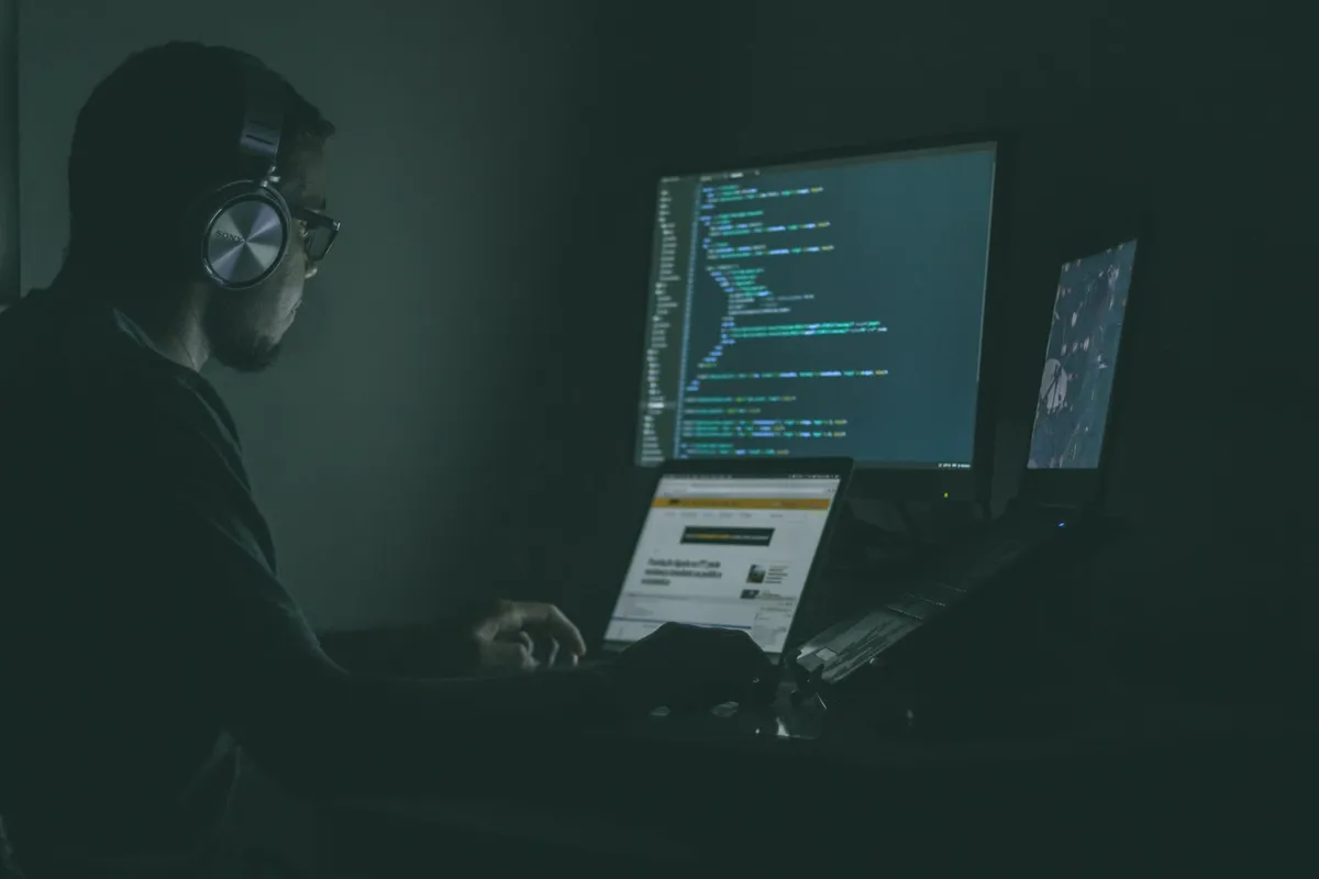 A man sitting at his desk late at night trying to debug his code