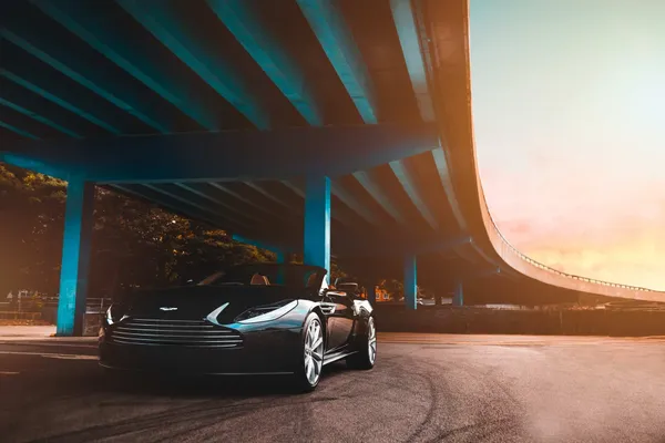 A convertible sports car under a bridge