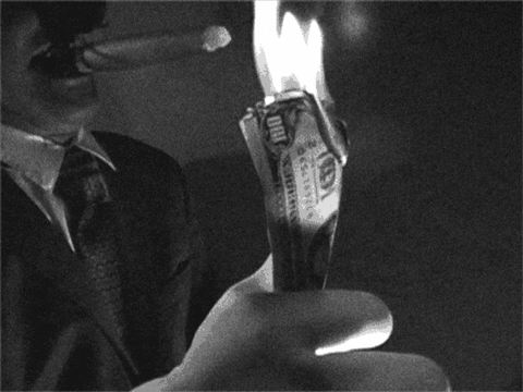 A man lighting a cigar with burning $100 bills