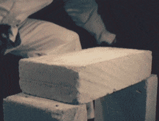 A man karate chopping and breaking a concrete block in half with his hand