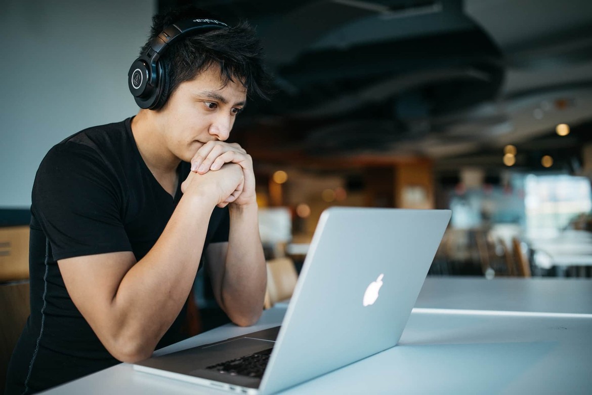 A man sitting at a desk and staring at his laptop