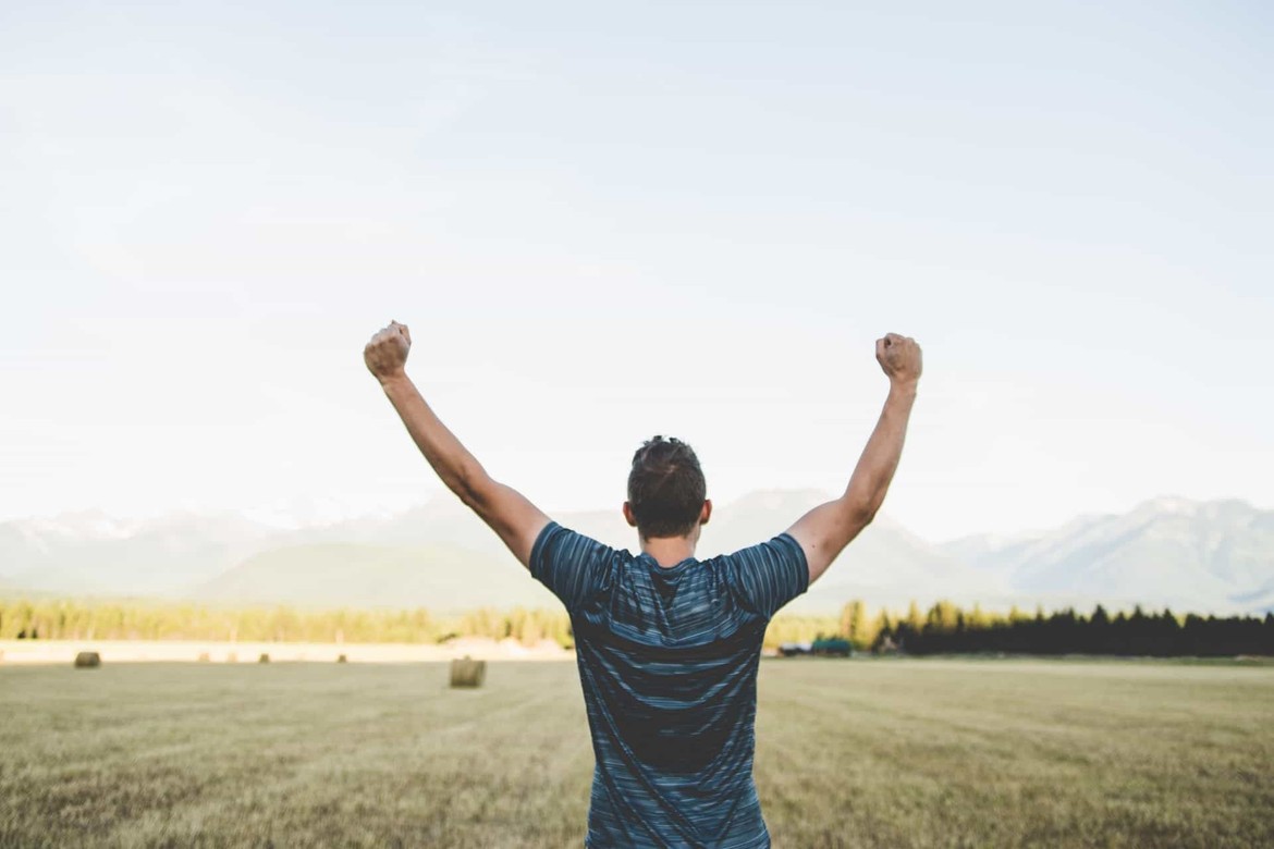 A man standing with his back to the camera and his arms up in the air