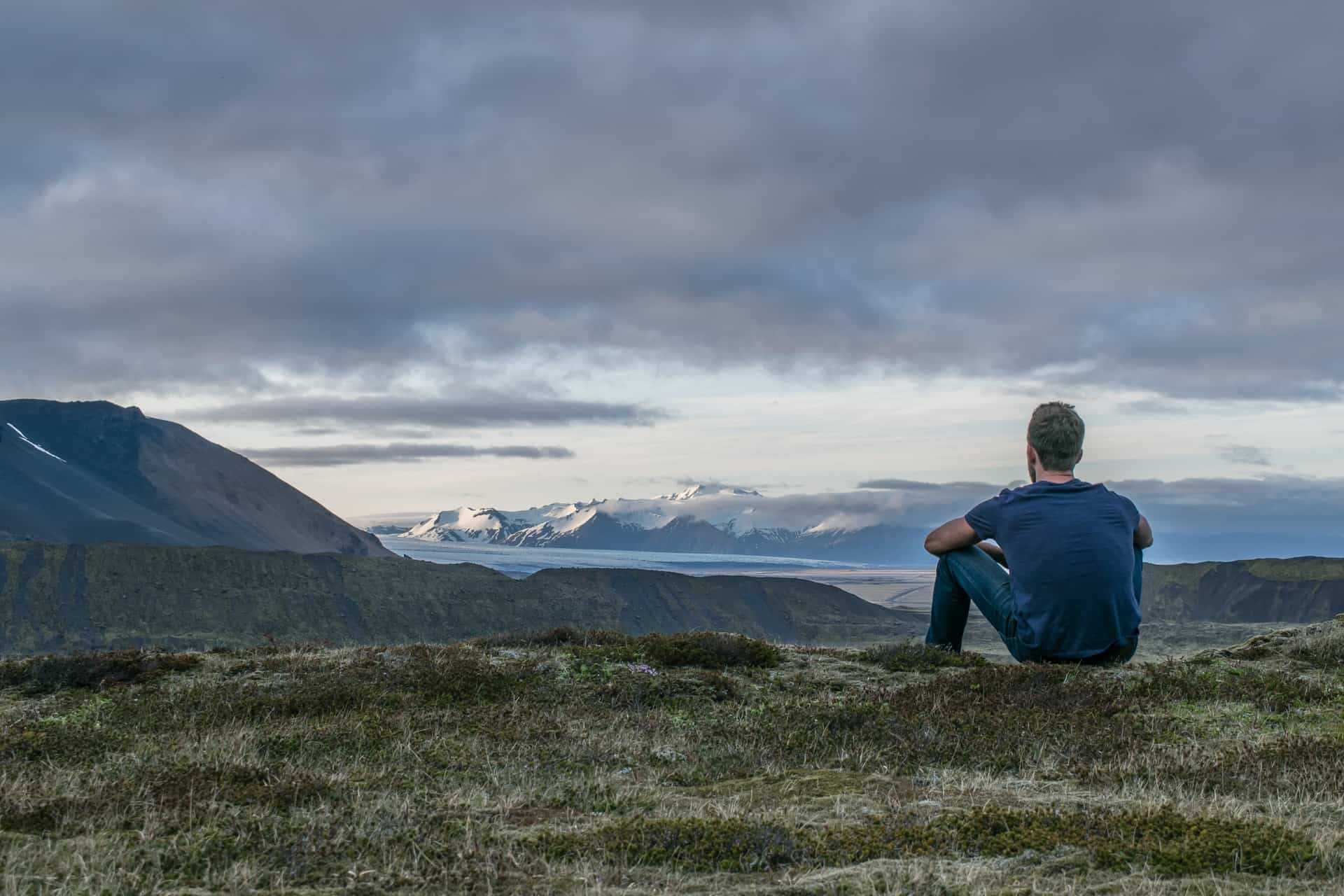 Man sitting down on grass in nature and near the mountains