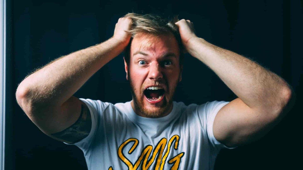 A man in angry with both of his hands in his hair