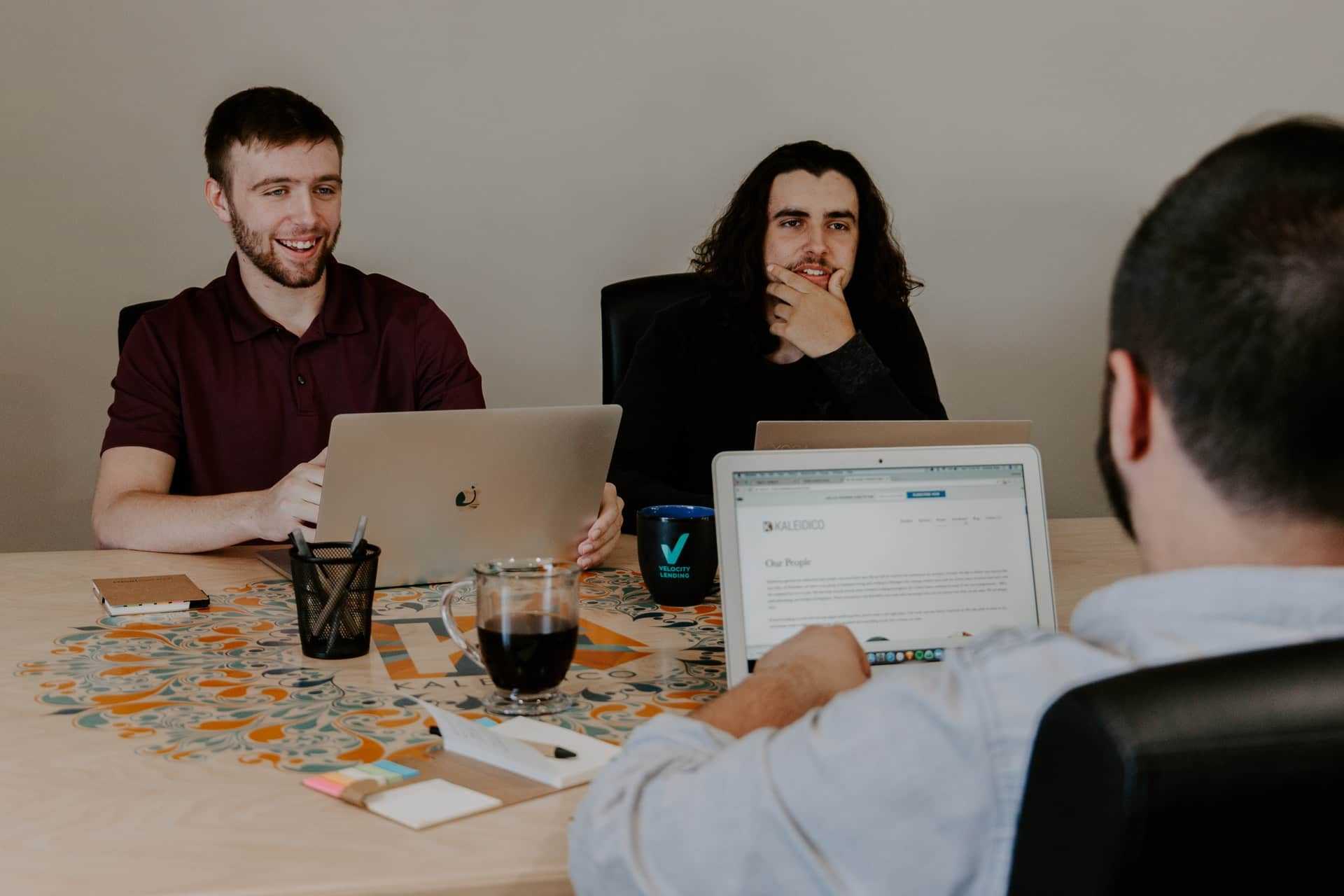 A few tech people with computers at a hackathon event.