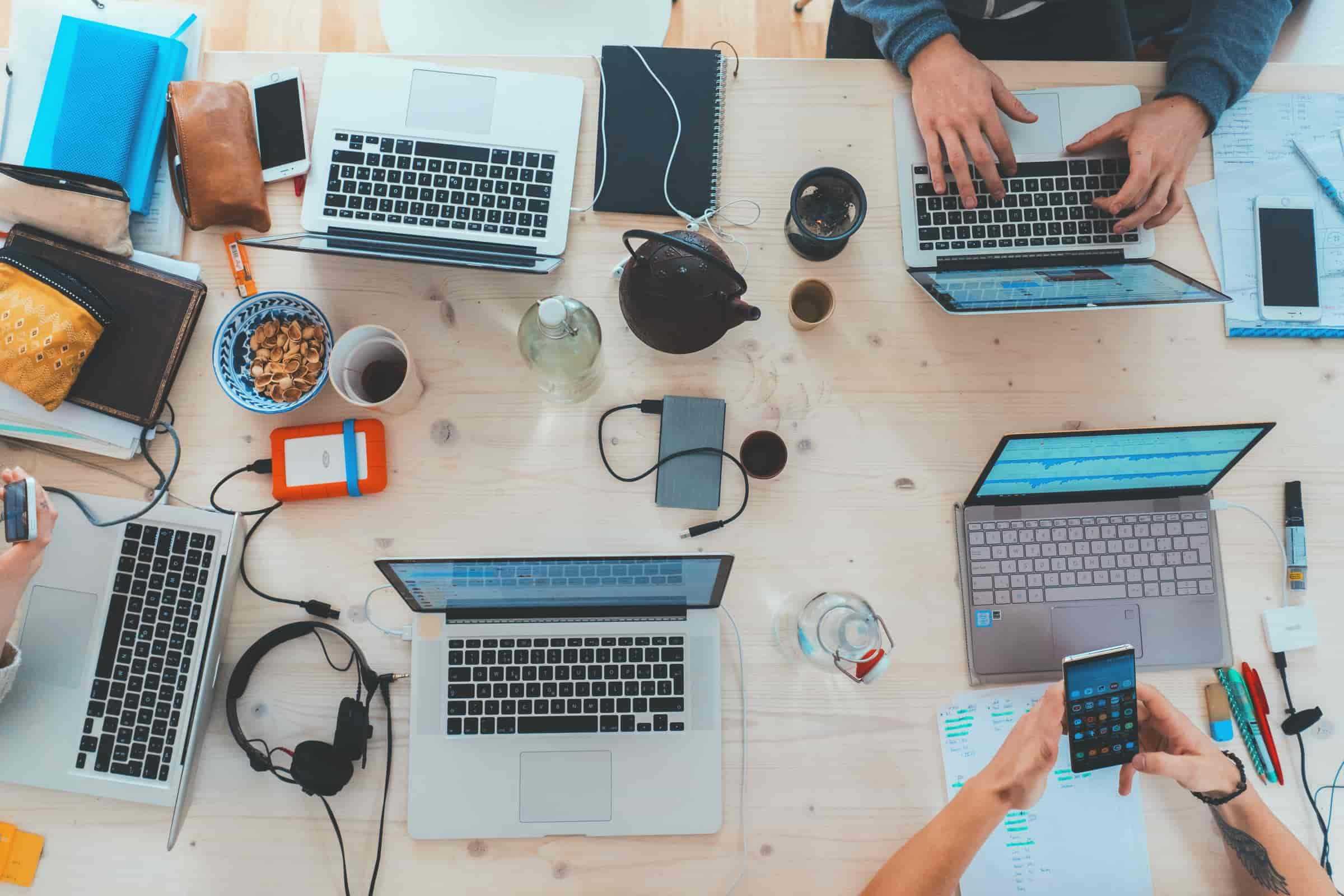 A group of people working at a table with their laptops.