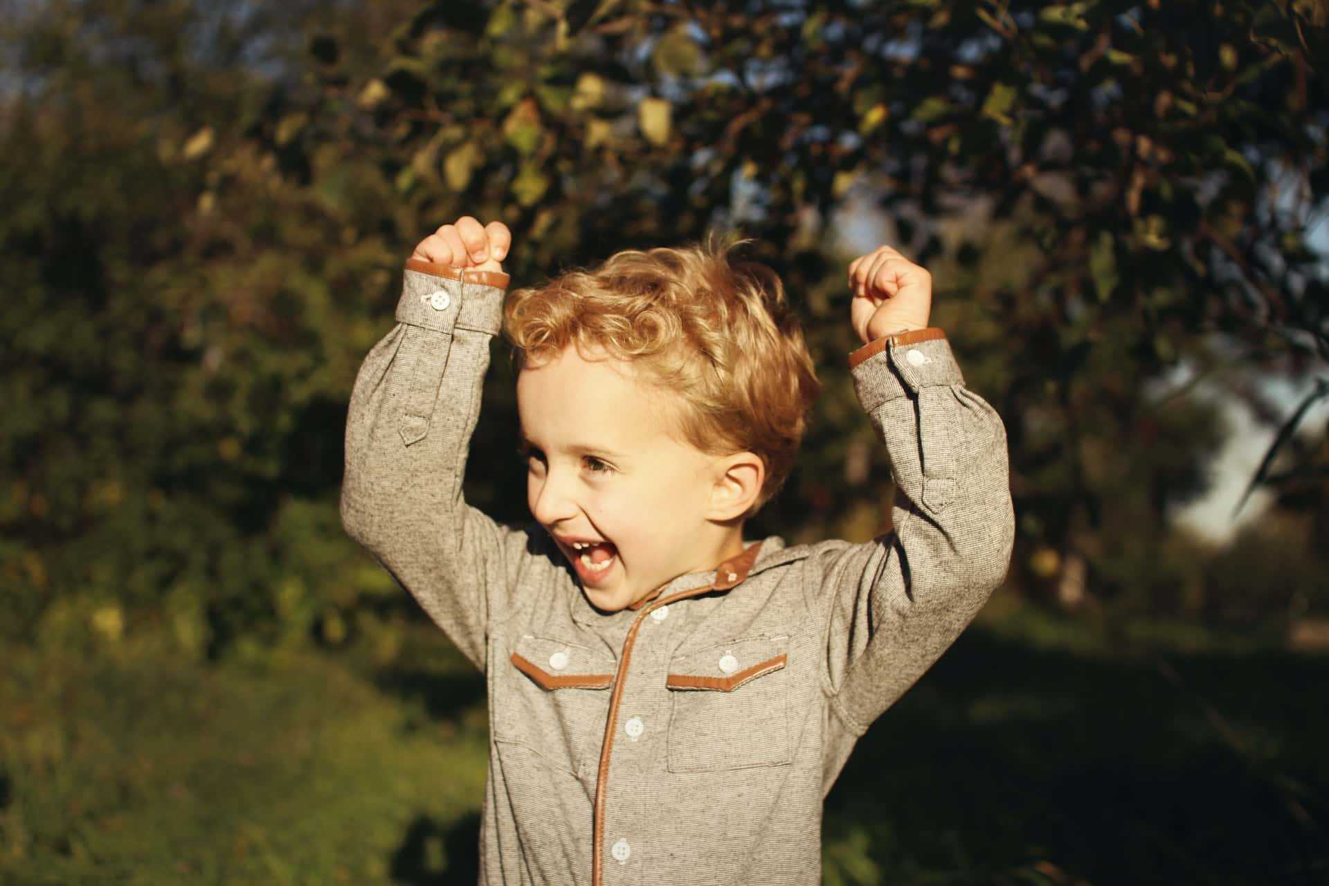 A small child with arms up in the air in excitement